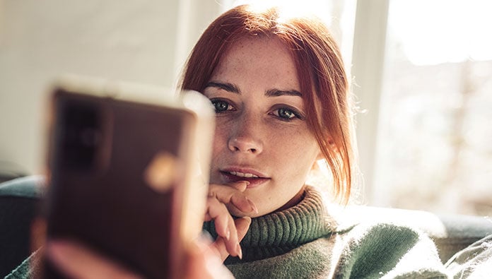 A woman deep in thought while looking at her phone A woman deep in thought while looking at her phone